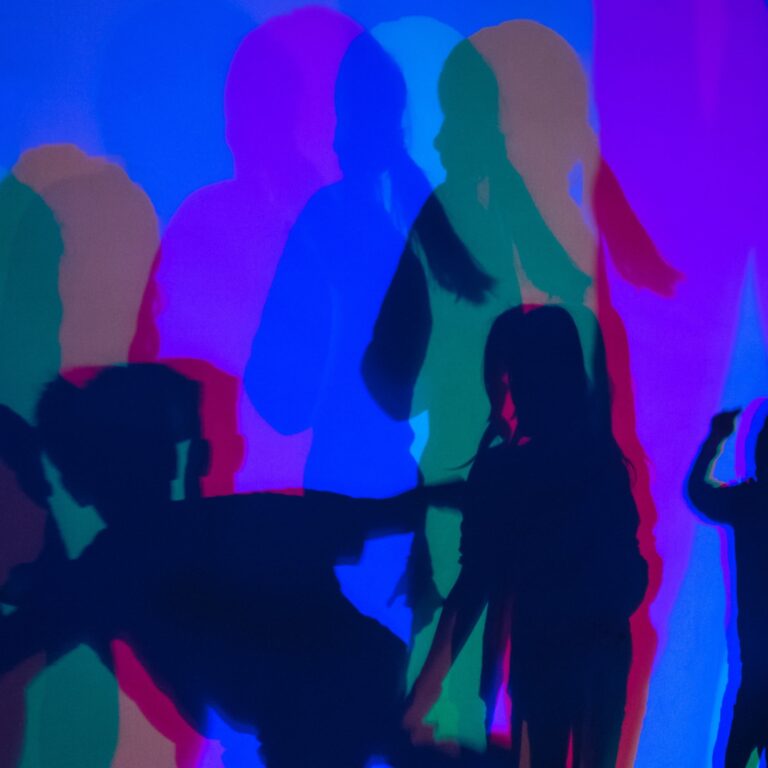 Mehrere farbige Schatten von Personen auf einer Wand, überwiegend in Blau, Rot und Grün.