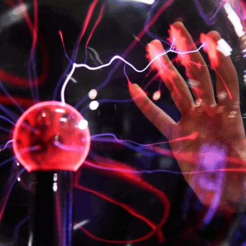 Hand berührt eine leuchtende Plasmakugel, aus der violette und rote elektrische Entladungen strahlen.